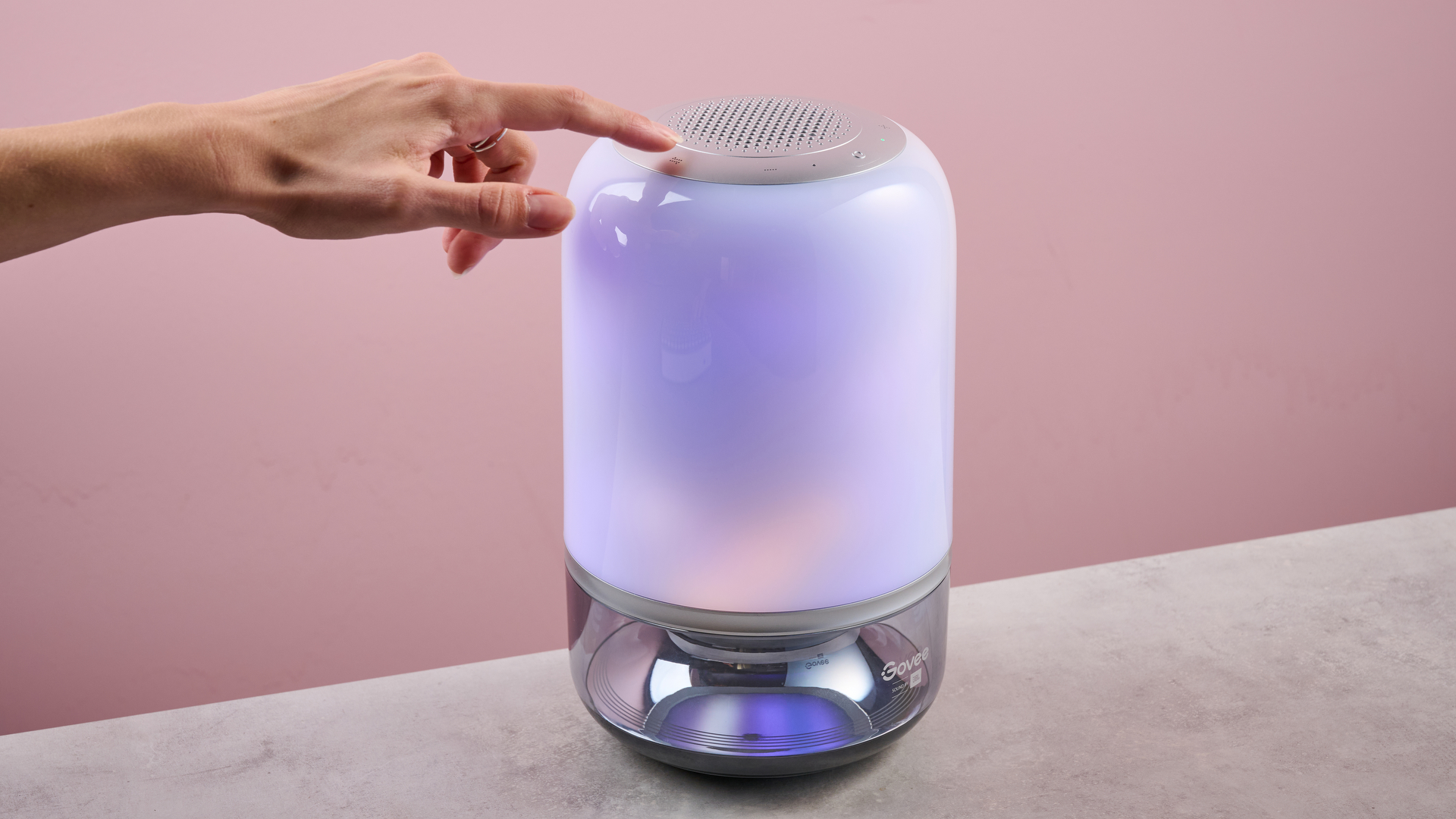 A woman is pressing one of the touch buttons on the top of the Govee Table Lamp 2 Pro x Sound by JBL.